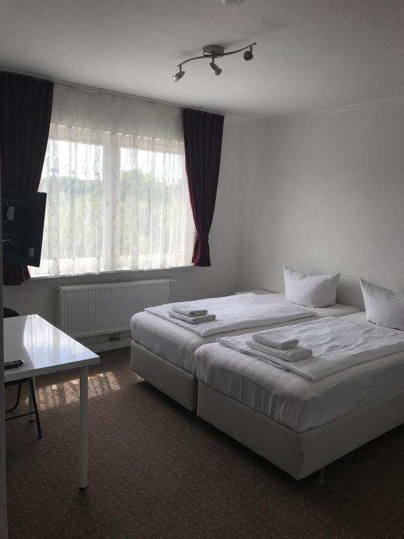a hotel room with two beds and a window at Hotel-Pension Alt-Heidenberg in Siegen