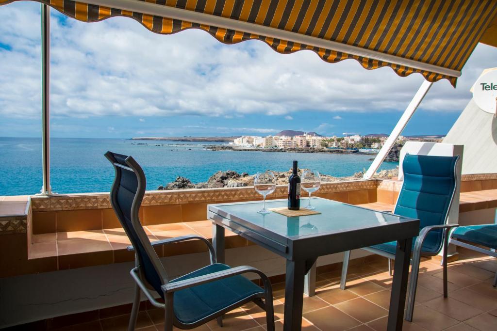 a table and chairs on a balcony with a view of the ocean at Listen THE VIEWS - 223 in Costa Del Silencio