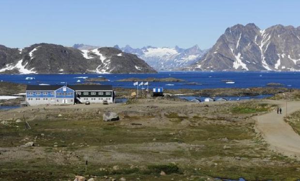 una casa en un campo con un lago y montañas en Hotel Kulusuk, en Kulusuk