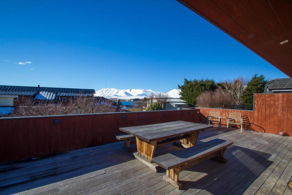 a wooden deck with a wooden table and benches at Kaltech House - Lake Tekapo in Lake Tekapo