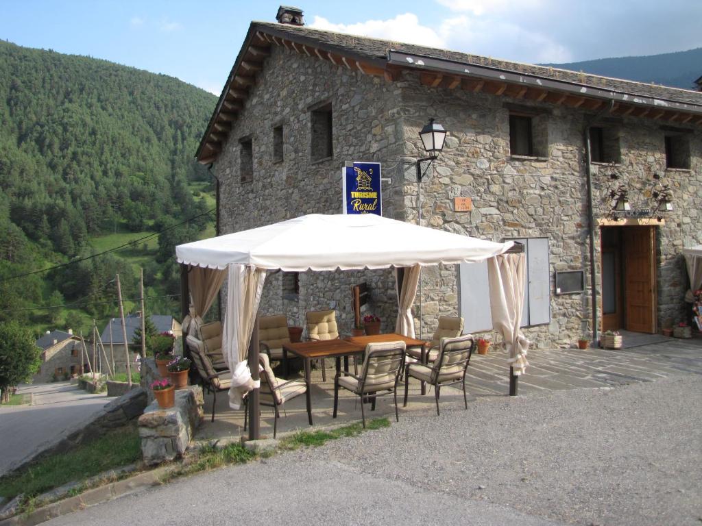 a table and chairs under an umbrella in front of a building at Cal Pastor in Fornells de la Muntanya