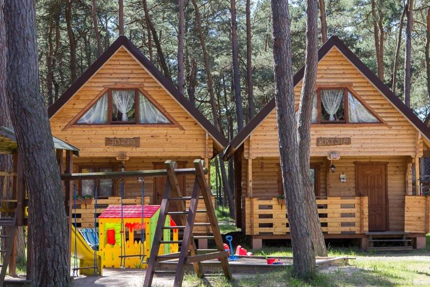 a log cabin with a playground in the woods at Sosnowa Mila in Pobierowo