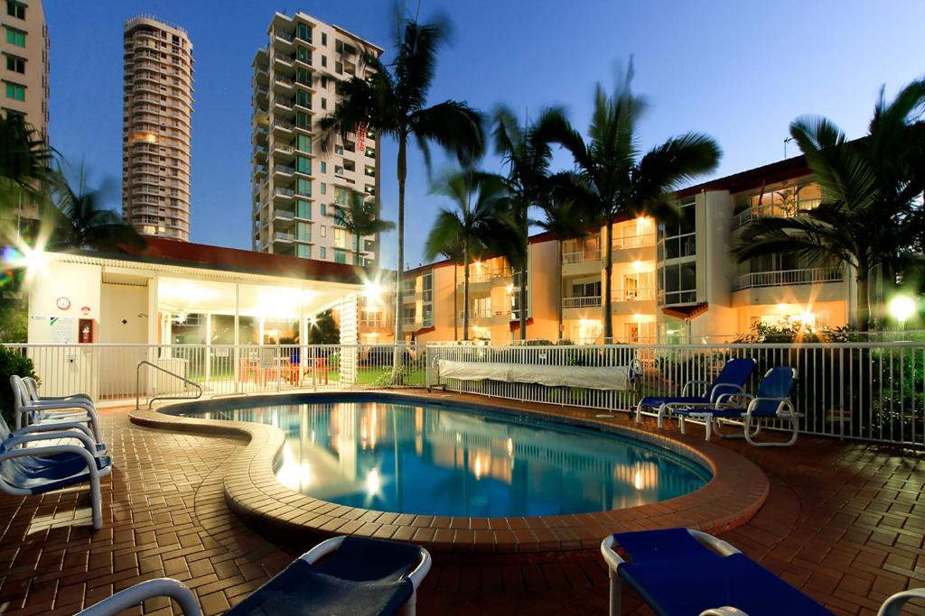 a swimming pool with chairs and a building at Key Largo Holiday Apartments in Gold Coast