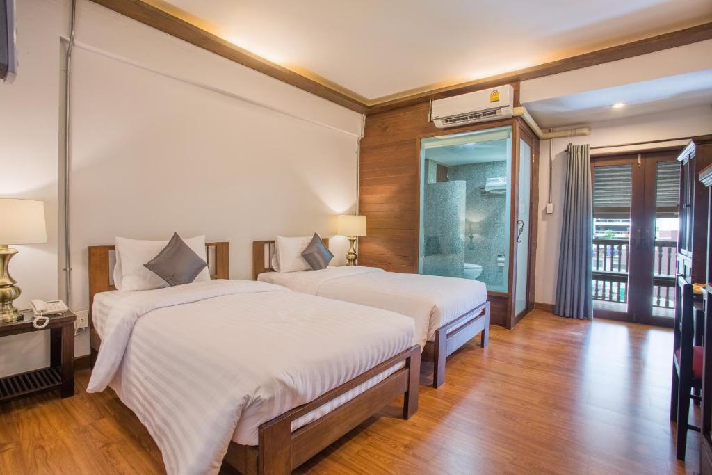 two beds in a room with wooden floors at Night Bazaar Inn in Chiang Mai