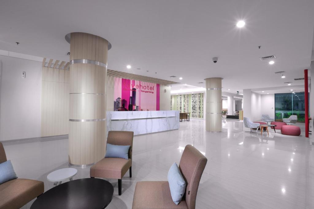 a lobby with chairs and tables in a building at favehotel Bandara Tangerang in Tangerang