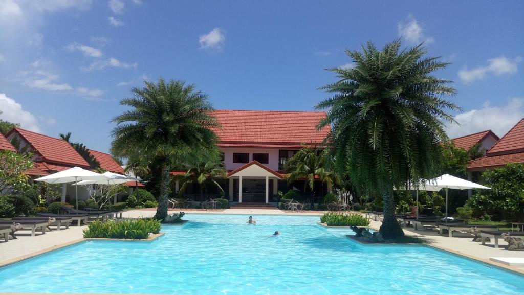 uma piscina com duas palmeiras em frente a um edifício em Armonia Village Resort and Spa em Chumphon