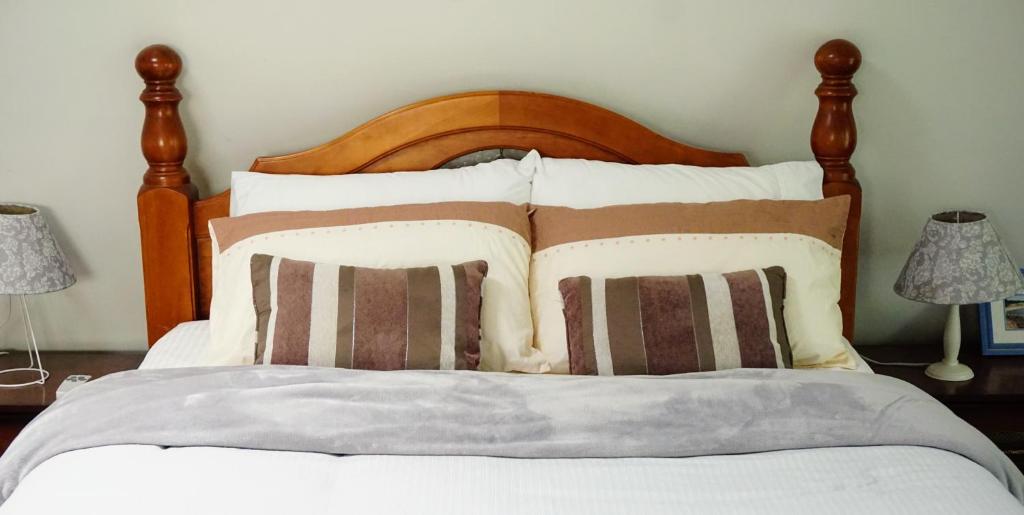 a bed with a wooden head board and pillows at Moon House in Diamond Creek