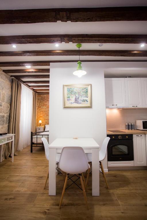 a kitchen with a white table and white chairs at Studio apartman Ana in Split