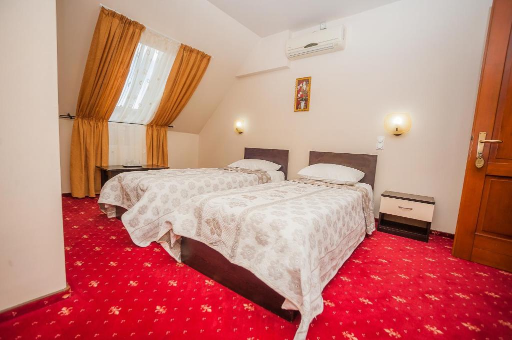 a hotel room with two beds and a red carpet at Vila Romance in Bistriţa