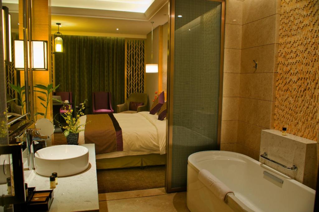 y baño con cama, bañera y lavamanos. en Yangzhong Firth Jinling Grand Hotel, en Yangzhong