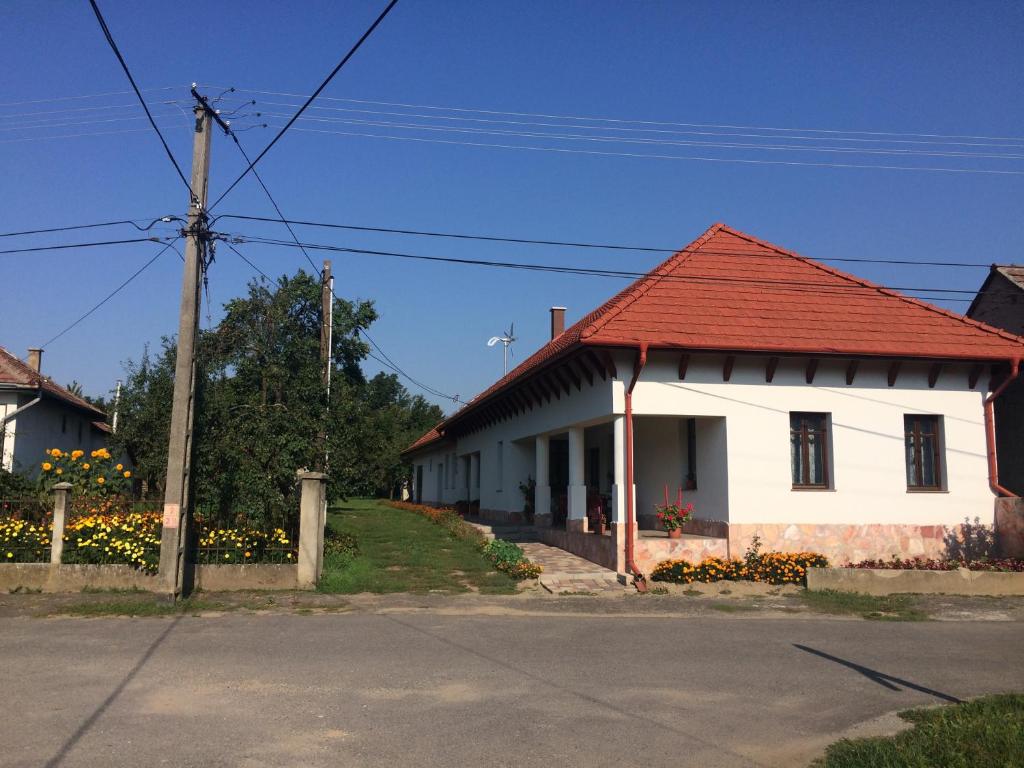 una casa blanca con techo rojo en una calle en Bajusz Vendégház, en Tornyosnémeti