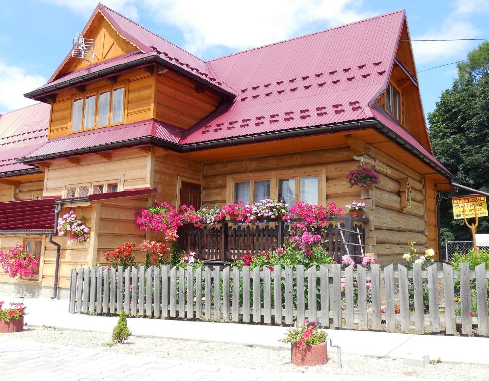 ein Holzhaus mit einem Zaun und Blumen in der Unterkunft Pokoje Pod Cyrlicą u Józi in Chochołów