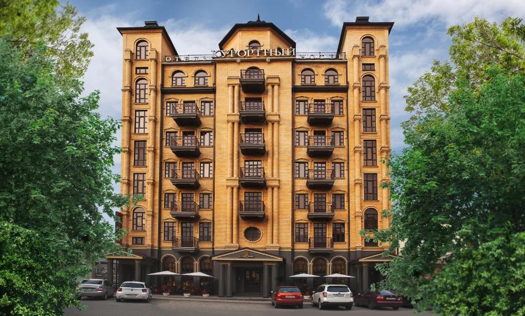 a large yellow building with cars parked in front of it at Hotel Kurortnyy in Essentuki