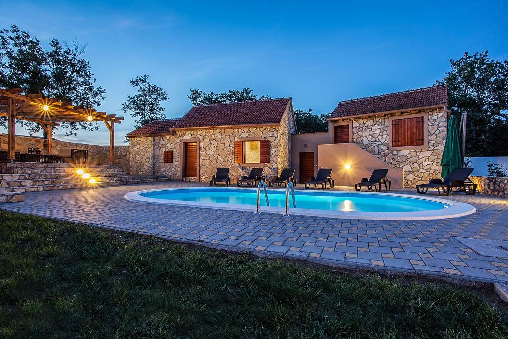 a swimming pool in front of a house at Villa Viktorija in Galovac