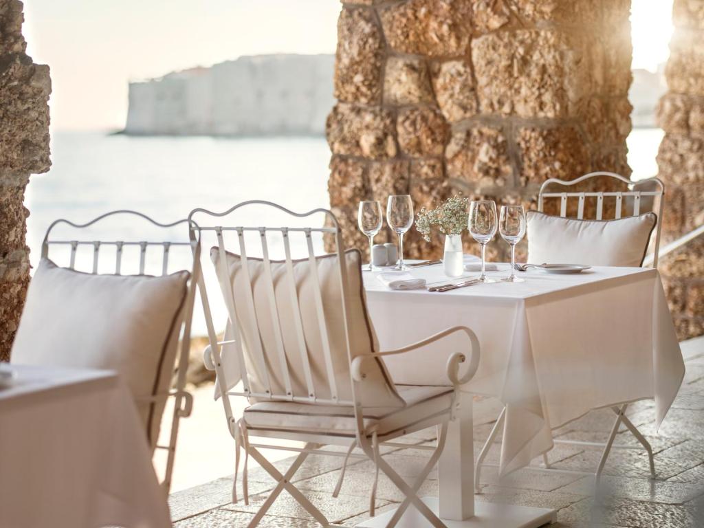 a white table and chairs with wine glasses on a balcony at Hotel Excelsior in Dubrovnik