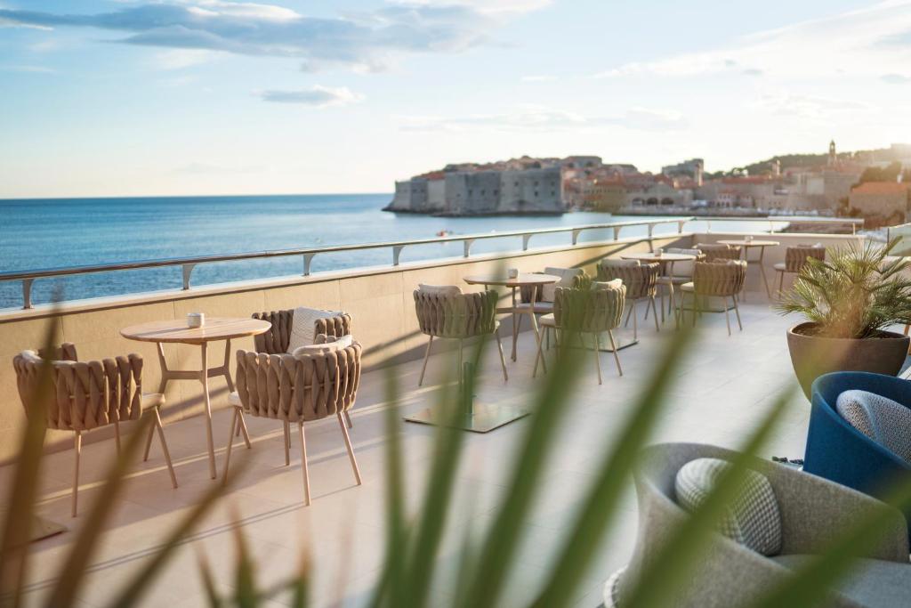 einen Balkon mit Tischen, Stühlen und Meerblick in der Unterkunft Hotel Excelsior in Dubrovnik