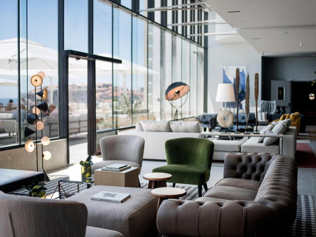 a living room with a couch and chairs and windows at Hotel Excelsior in Dubrovnik