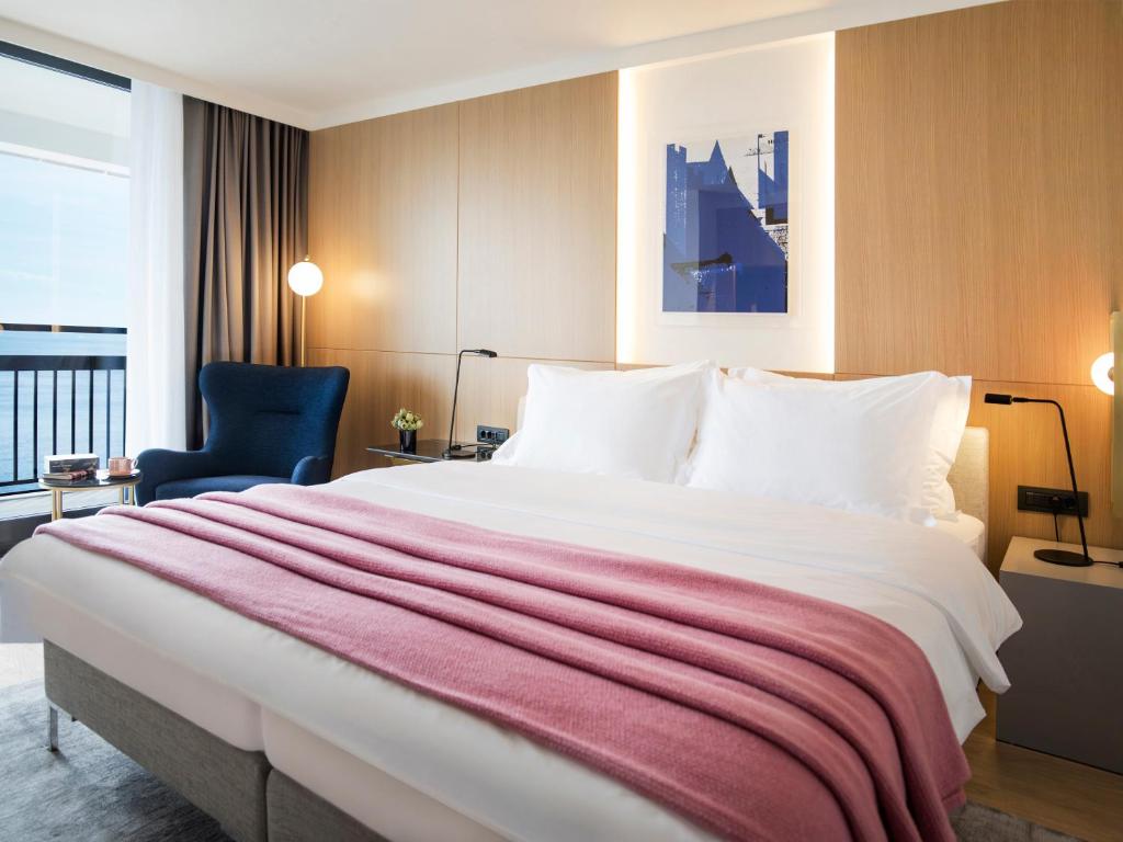 a hotel room with a large bed and a chair at Hotel Excelsior in Dubrovnik