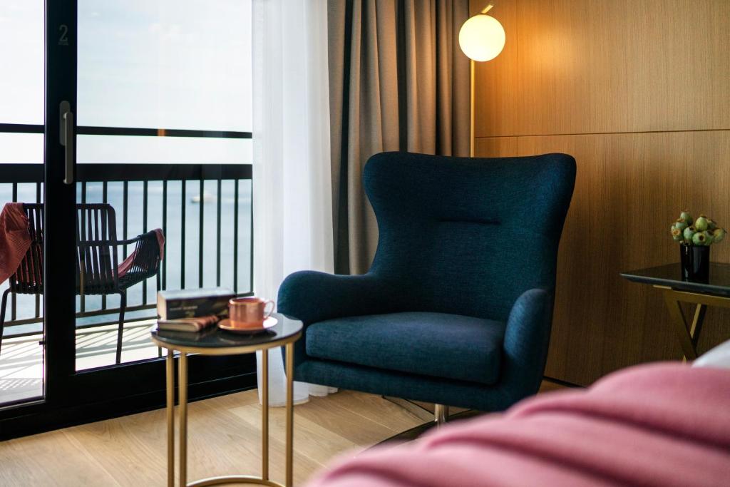 a living room with a blue chair and a balcony at Hotel Excelsior in Dubrovnik