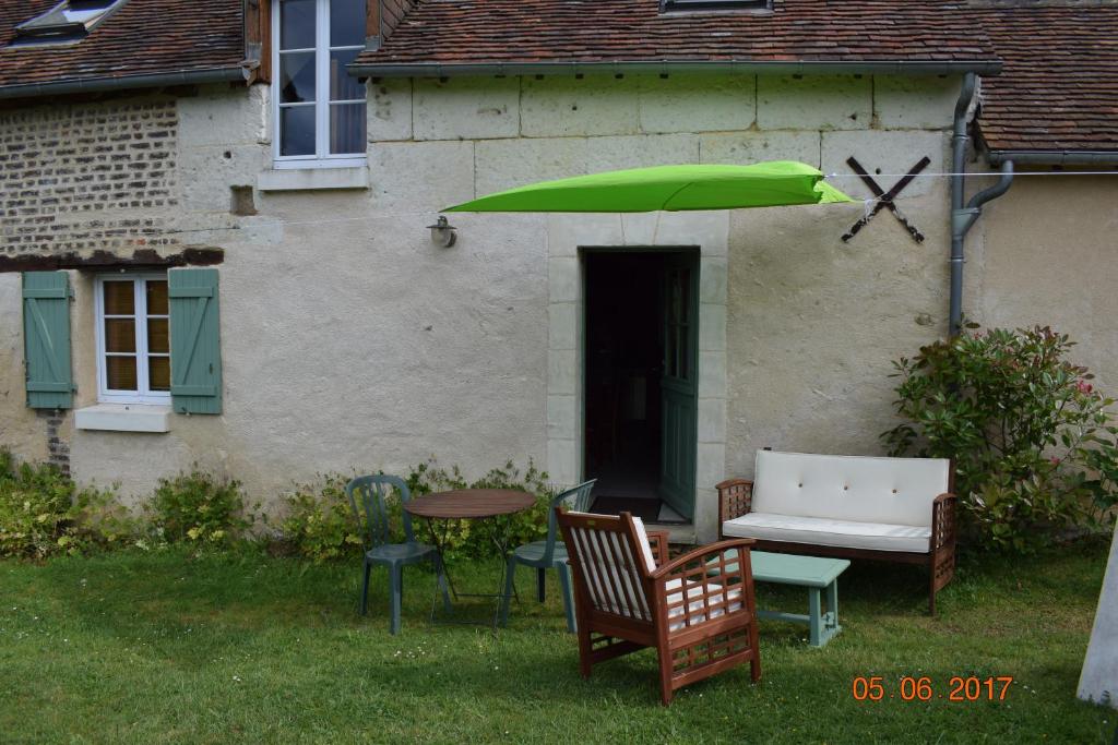 une table, des chaises et un parasol en face d'une maison dans l'établissement Au calme, à Houssay