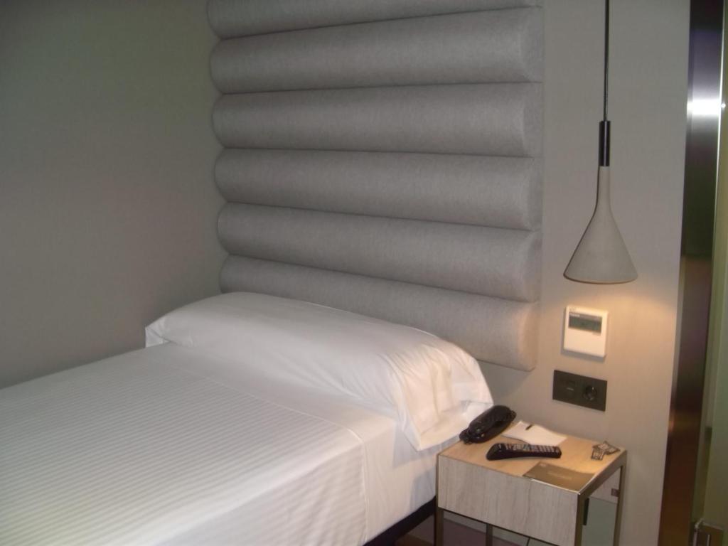 a bedroom with a bed and a table with a phone at Zenit Vigo in Vigo