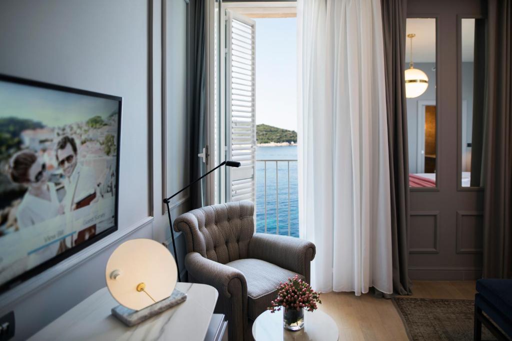 a living room with a chair and a large window at Hotel Excelsior in Dubrovnik