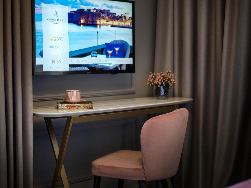 a table with a chair and a television on a wall at Hotel Excelsior in Dubrovnik