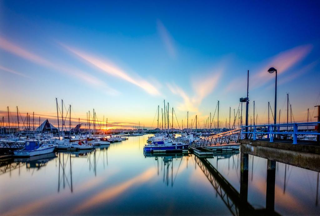 a group of boats docked in a marina at sunset at Duplex Villa Capricia appartement met zwembad Nieuwpoort Jachthaven in Nieuwpoort