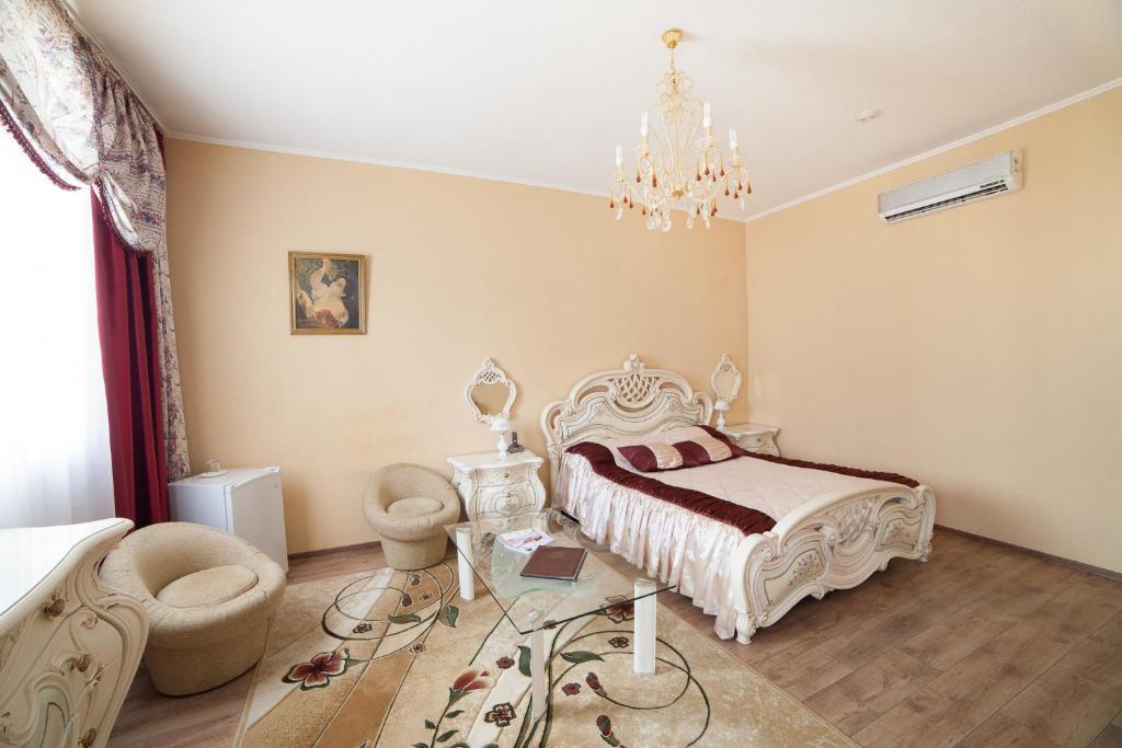 een slaapkamer met een bed, een tafel en een kroonluchter bij Family Hotel in Kurgan