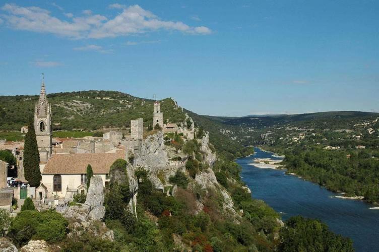 a castle on top of a hill next to a river at La fontaine in Aiguèze