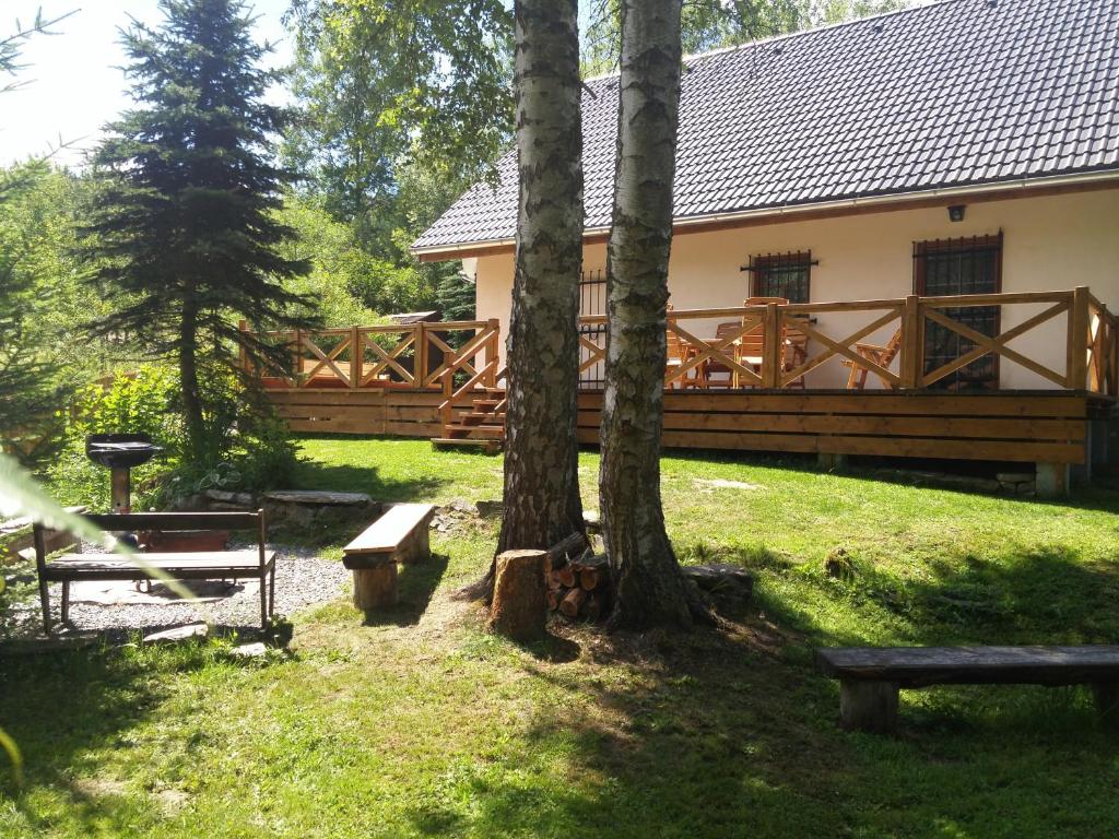 ein Haus mit einem Holzzaun sowie Bäumen und Bänken in der Unterkunft Polosamota pod Kašperkem Příčná in Dlouhá Ves