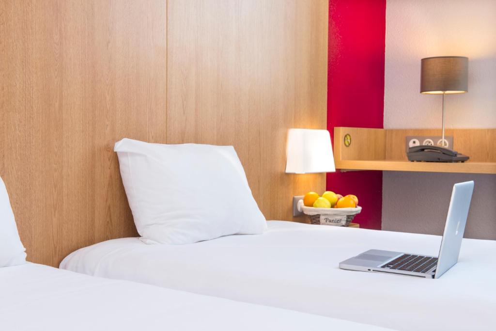 a hotel room with a bed with a laptop on it at B&B HOTEL La Rochelle Centre in La Rochelle