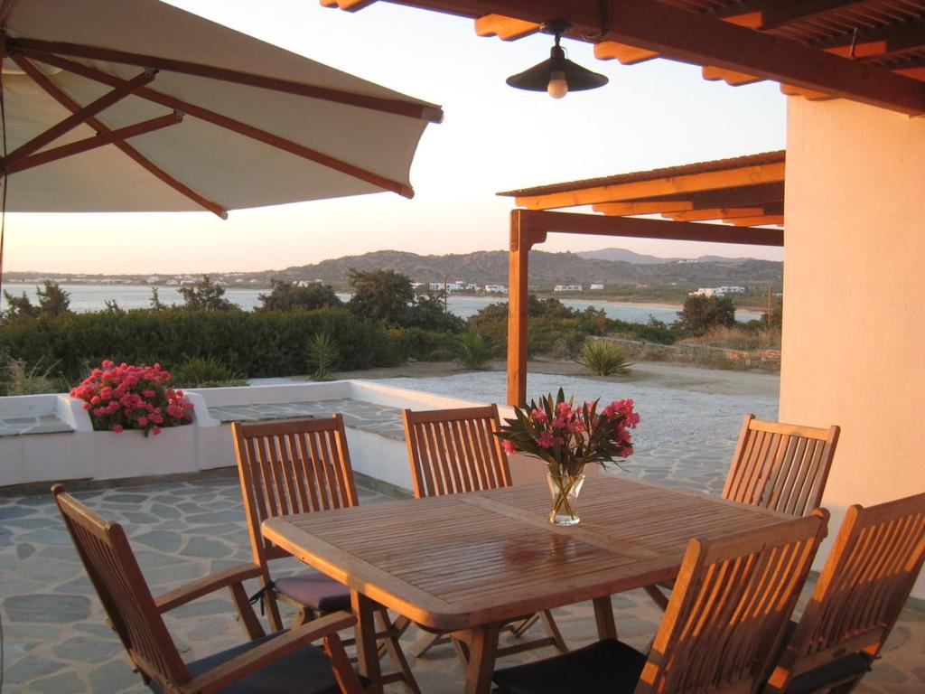 a wooden table with chairs and a vase of flowers at Naxos Beachvilla in Plaka