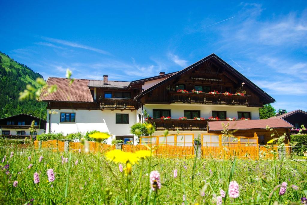 um edifício com uma varanda num campo de flores em Haus Kohlberghof em Bichlbach