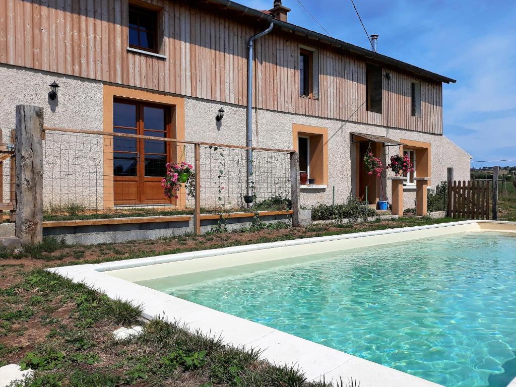 a swimming pool in front of a house at La ferme du Bouton d'Or in Vendranges