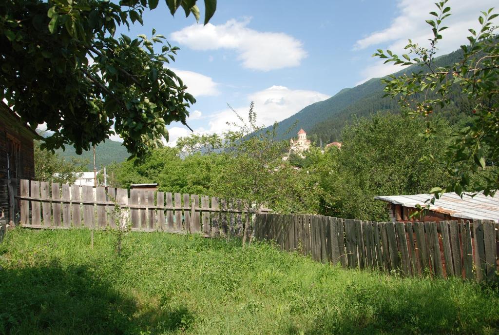 a wooden fence in a yard with mountains in the background at Keti Pilpani Guesthouse in Mestia