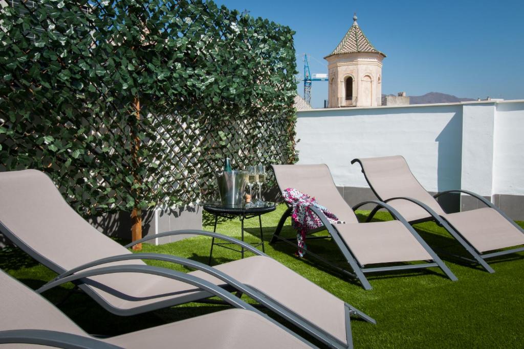 eine Gruppe Stühle und ein Tisch auf einer Terrasse in der Unterkunft Holidays2Malaga Suites in Málaga