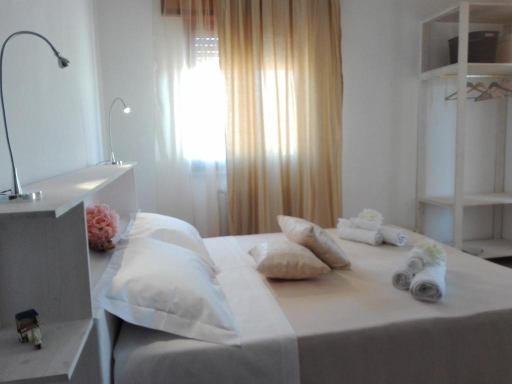 ein Schlafzimmer mit einem weißen Bett mit Kissen und einem Fenster in der Unterkunft Bed and Breakfast Elettra in Marconia