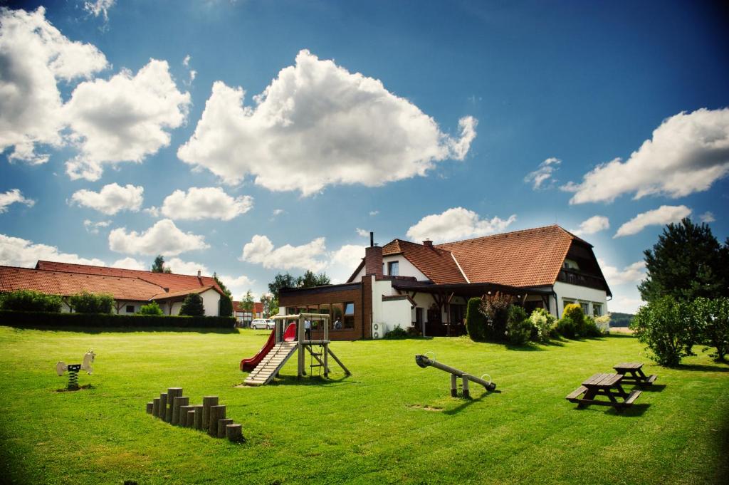 um quintal com um parque infantil em frente a uma casa em Hotel Farma em Pelhřimov