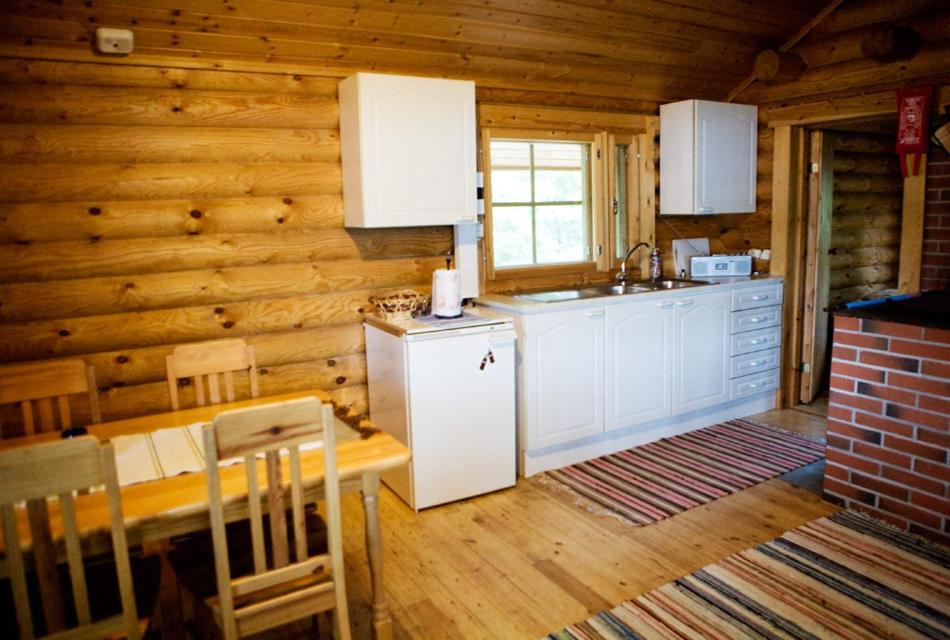 OrivesiにあるPielppa Lodgeの白いキャビネットと木製の壁が備わるキッチン