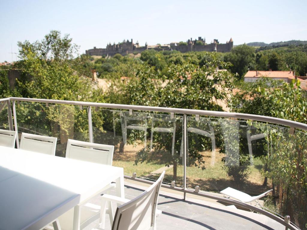 balcón con sillas blancas y vistas al jardín en Appartement Le Saint Nazaire - Les Balcons de la Cité, en Carcassonne
