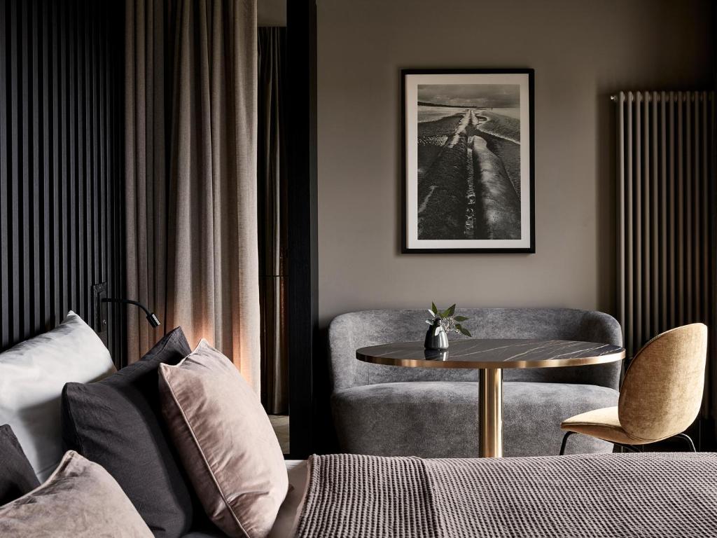 a living room with a couch, chair, table and lamp at Mauritzhof Hotel Münster in Münster