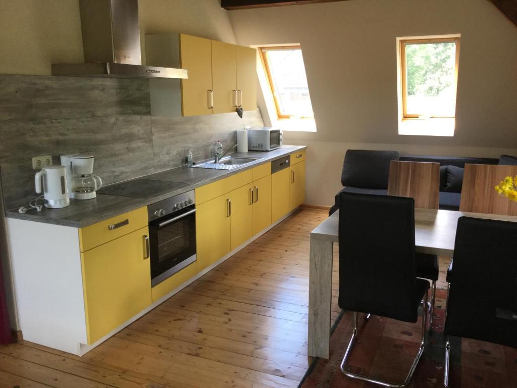 eine Küche mit gelben Schränken und einem Tisch mit Stühlen in der Unterkunft Ferienwohnung Saaleblick in Halle an der Saale