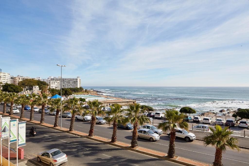 una calle bordeada de palmeras junto al océano en First Group Riviera Suites en Ciudad del Cabo