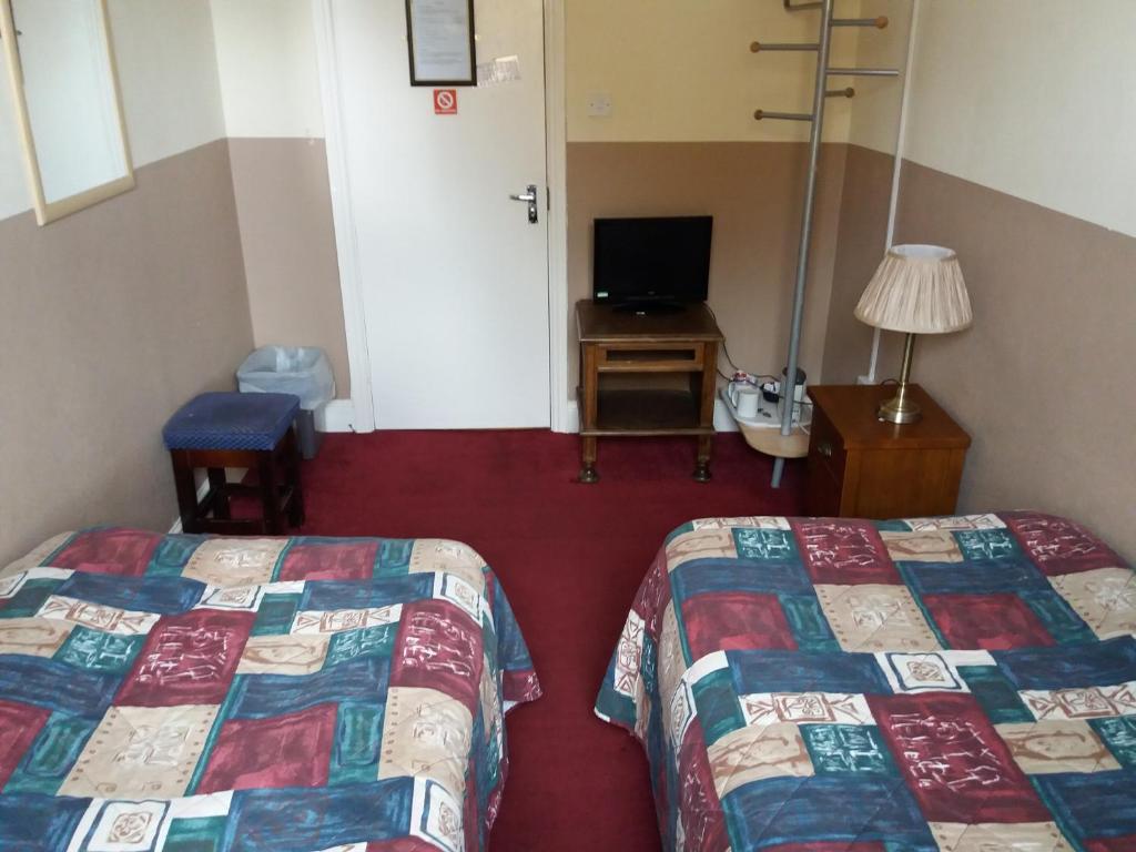um quarto de hotel com duas camas e uma televisão em The Crouch Oak em Addlestone