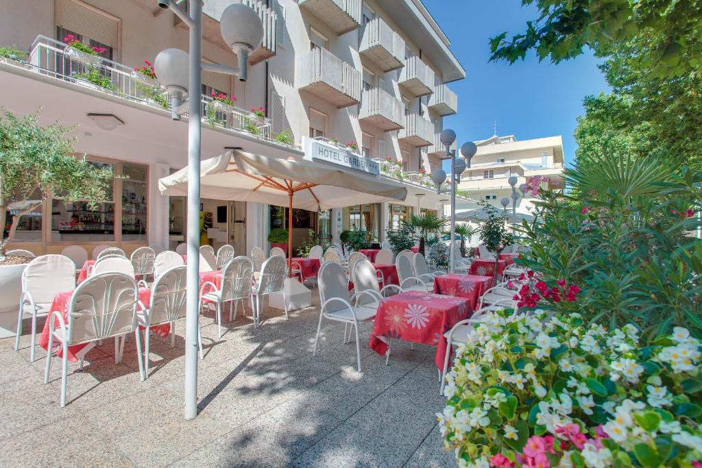 un gruppo di tavoli e sedie di fronte a un edificio di Hotel Garden a Bellaria-Igea Marina