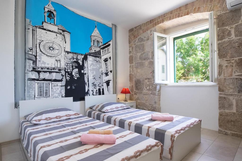 twee bedden in een kamer met een muurschildering aan de muur bij Tamaria in Split