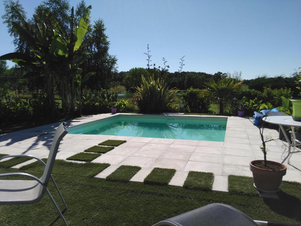 una piscina en un patio con mesa y sillas en Maison à la campagne en Lavergne