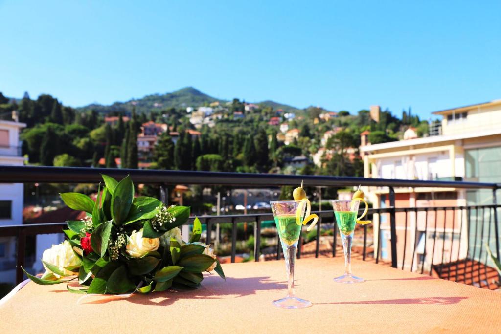 two wine glasses and a flower arrangement on a balcony at Hotel Alla Fontanella in Alassio