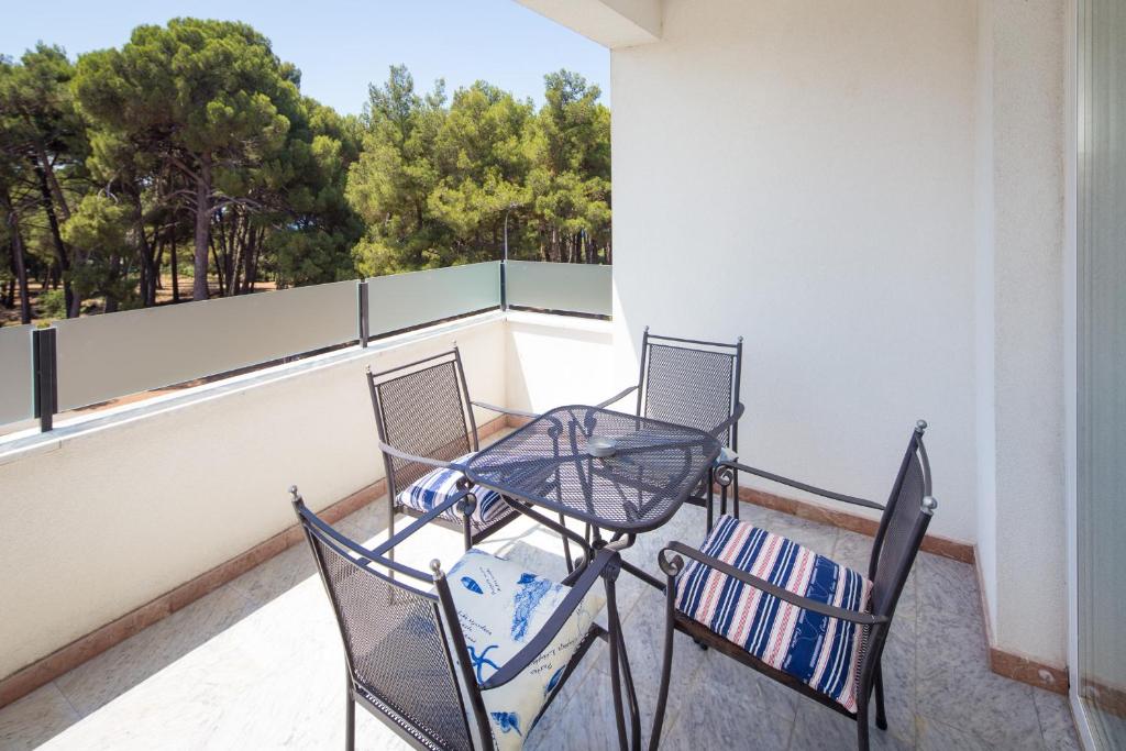 a table and chairs on a balcony with a view of trees at Apartments Tamburini in Rovinj